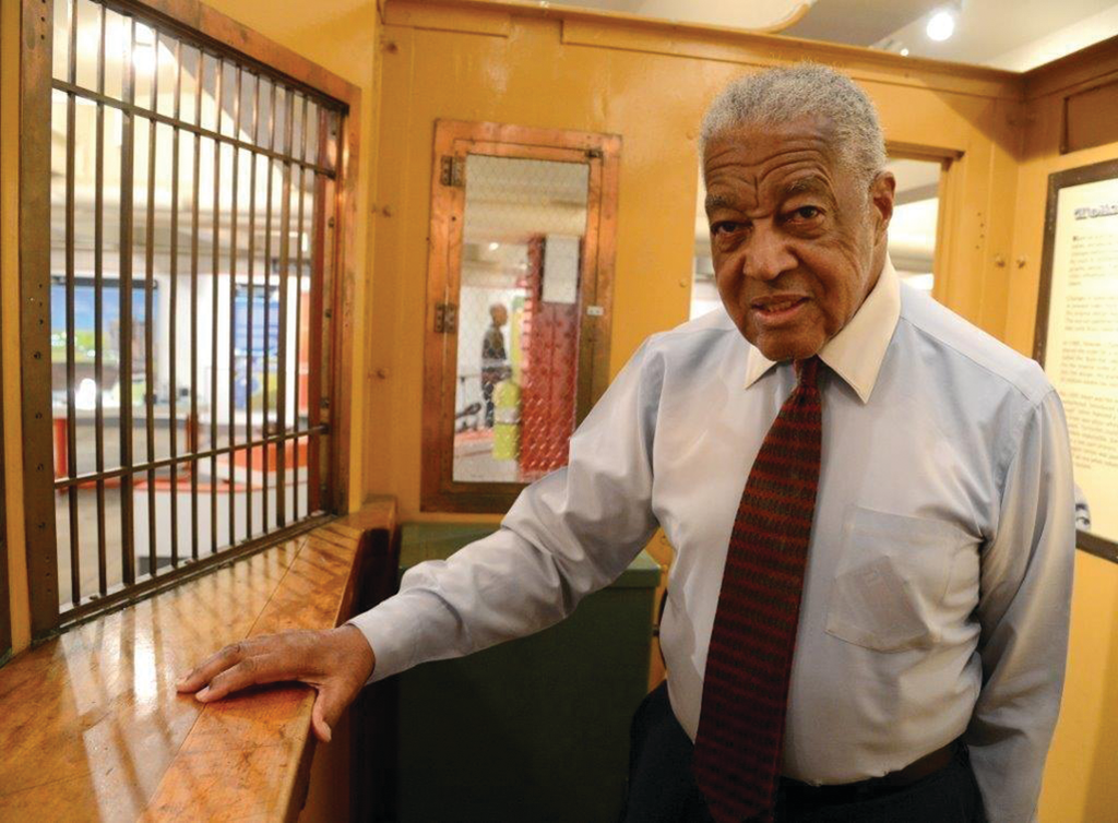 Retired Station Supervisor Thomas Merrick inside restored subway change booth at New York Transit Museum.