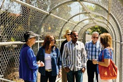 Externship participants are briefed on the Exposition Light Rail Line project by Exposition Metro Line Construction Authority COO Samantha Bricker as they cross a pedestrian bridge that spans the tracks.