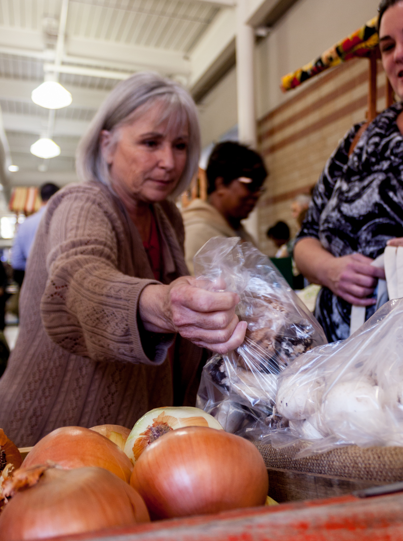 A shopper takes advantage of The Market opening to select fresh mushrooms.