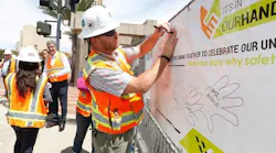 A transit construction worker draws his handprint on a Safety Week 2017 banner to demonstrate his commitment to safety.