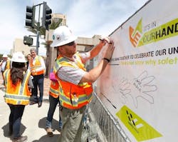 A transit construction worker draws his handprint on a Safety Week 2017 banner to demonstrate his commitment to safety. A transit construction worker draws his handprint on a Safety Week 2017 banner to demonstrate his commitment to safety.