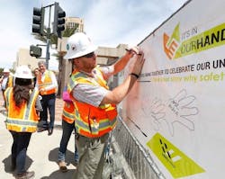 A transit construction worker draws his handprint on a Safety Week 2017 banner to demonstrate his commitment to safety.