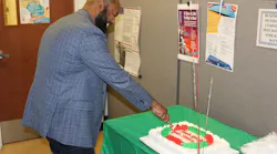 Executive Director Forbes caught in action cutting the first slice of cake during the National Customer Service Week closing celebration.