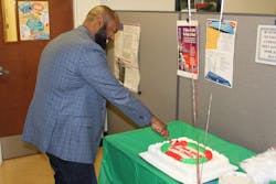Executive Director Forbes caught in action cutting the first slice of cake during the National Customer Service Week closing celebration.