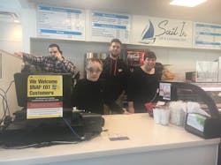 Sail In students and staff pose behind the counter at the Sail In Café. From left to right: Josh Feher (Sail In employee), David Kemske (student), Kyle Duffy (Community Enterprises job trainer), and Kim London (student). Sail In students and staff pose behind the counter at the Sail In Café. From left to right: Josh Feher (Sail In employee), David Kemske (student), Kyle Duffy (Community Enterprises job trainer), and Kim London (student).