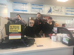 Sail In students and staff pose behind the counter at the Sail In Caf&eacute;. From left to right: Josh Feher (Sail In employee), David Kemske (student), Kyle Duffy (Community Enterprises job trainer), and Kim London (student).