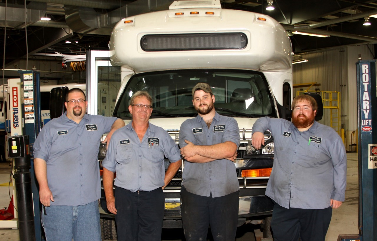 Four Heroes (pictured, L to R): Doug Gougeon, Larry Lautner, Steven Markel and John Baxter in front of a Blue Water Area Transit bus in the agency&rsquo;s garage.