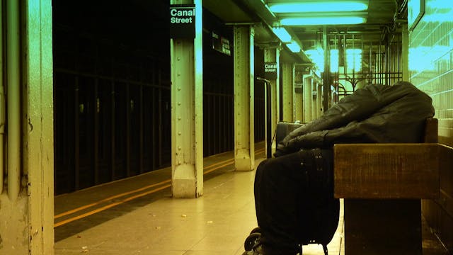 In this 2010 image, a homeless man sleeps on a bench on a NYC subway platform.