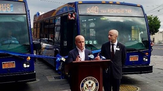 Matt Rose, at podium, and NYCT President Andy Byford at an event welcoming the new buses to Staten Island.