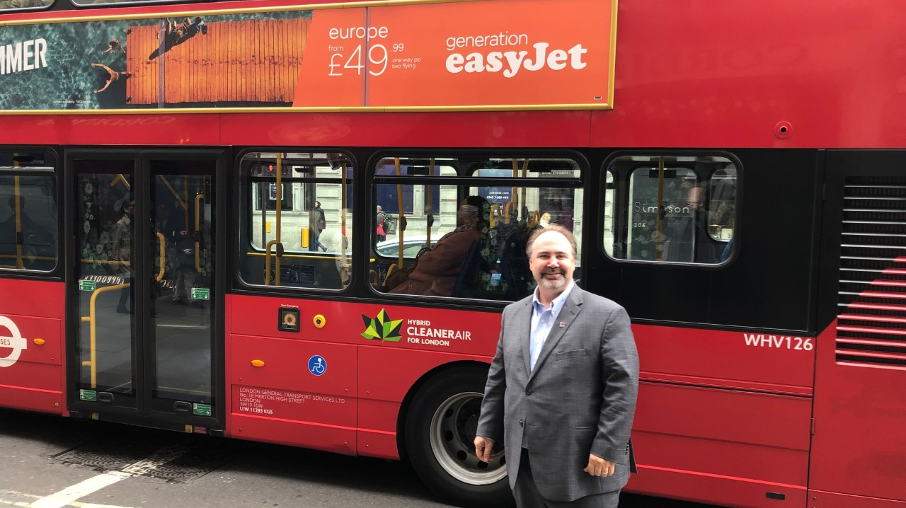 Paul stands by one of the iconic Red Transport for London public buses.