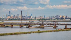 An Amtrak train crosses the Portal North Bridge with New York City in the background. An Amtrak train crosses the Portal North Bridge with New York City in the background.
