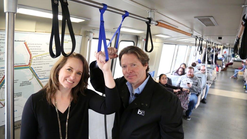 BART Chief Communications Officer Alicia Trost and General Manager Bob Powers demonstrate a prototype personal handstrap.