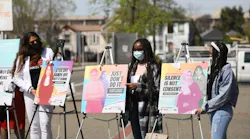 Youth activists Rexy, Uche, and Victoria with posters at launch of Not One More Girl campaign.