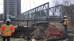 A crane helps lower the new steel bridge into place. A crane helps lower the new steel bridge into place.