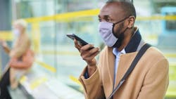 A rider dons a mask while waiting in a station. A rider dons a mask while waiting in a station.