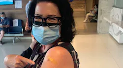 Anne Marie Aikins, head of media and public relations, proudly shows proof of her COVID-19 jab.