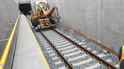 In this July 2021 photo, crews lay third rail by the track for the yard lead tunnel approach structure in Harold Interlocking.