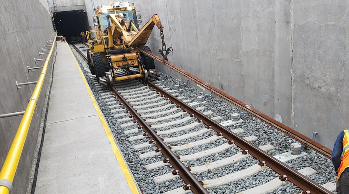 In this July 2021 photo, crews lay third rail by the track for the yard lead tunnel approach structure in Harold Interlocking.
