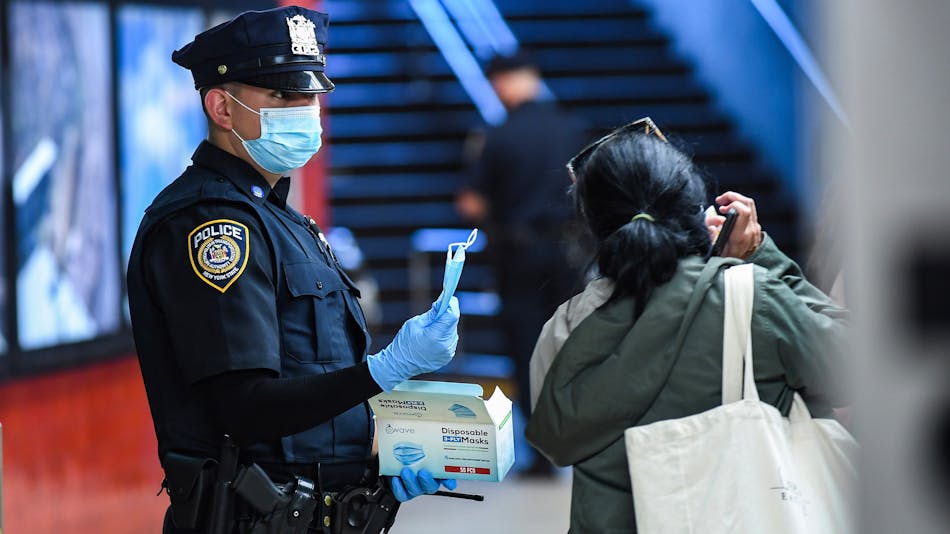 An MTA Police Officer distributes masks to MTA riders on Sept. 22; the authority plans to step up efforts to enforce proper mask wearing among riders.