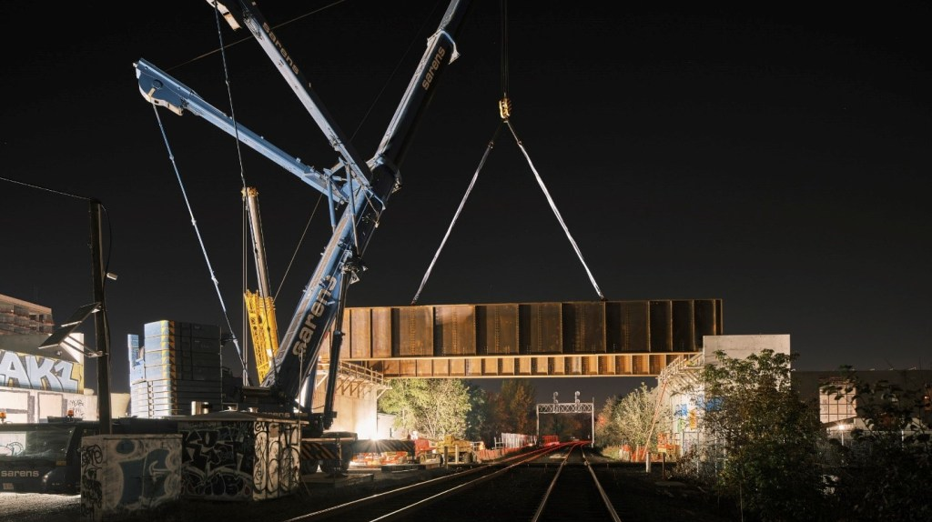 The steel girders are lifted into place by crane.