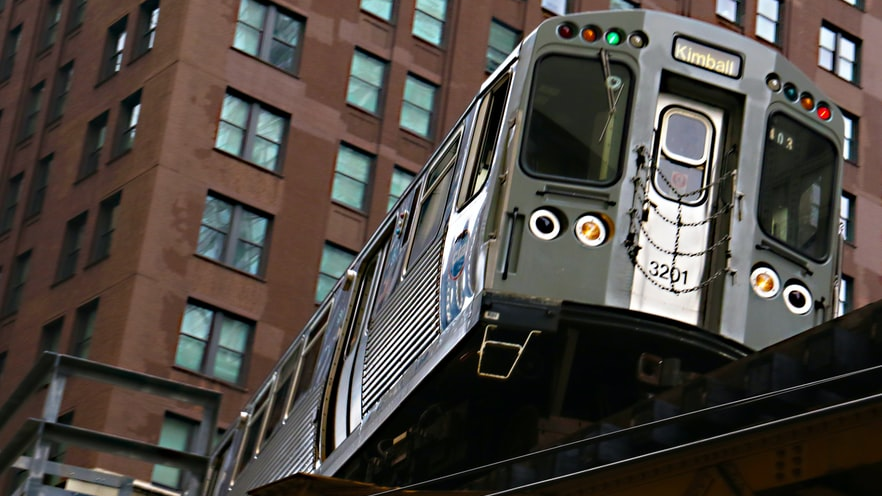A CTA Brown Line train to Kimball travels on elevated tracks in downtown Chicago.