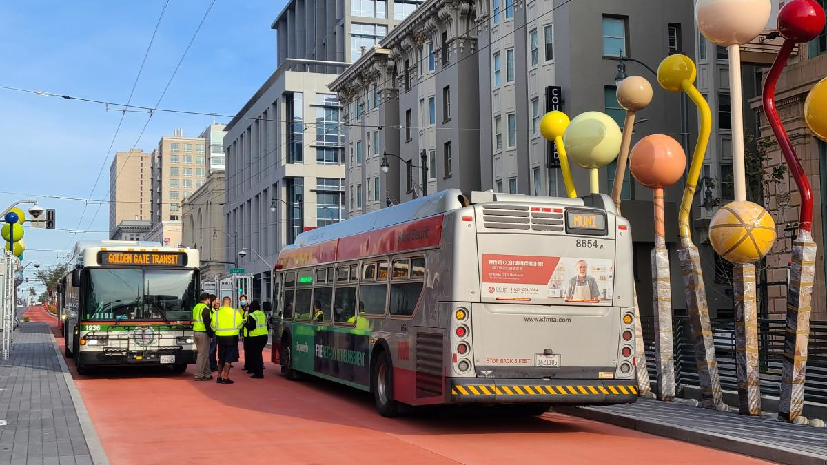 Staff measure passing distances between a Golden Gate Transit bus and a Muni bus at the Geary-O'Farrell BRT stop, where public artwork is being installed.