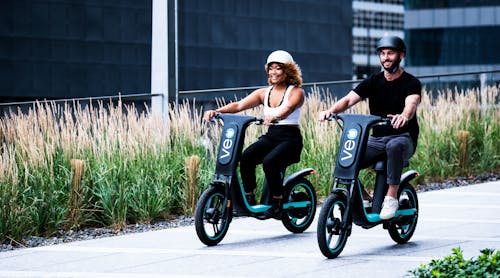 A couple riding the original Cosmo 1 seated scooter.