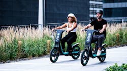 A couple riding the original Cosmo 1 seated scooter.