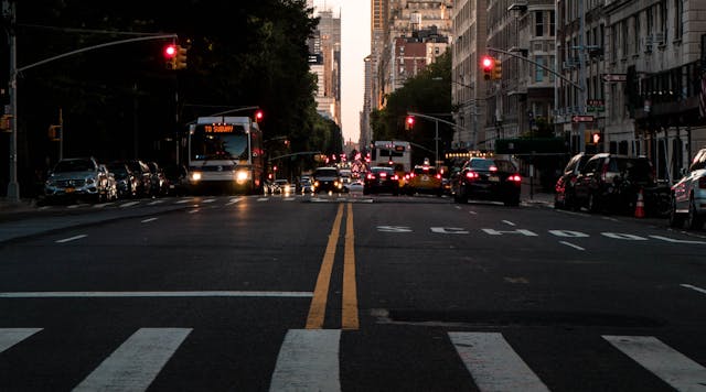 A New York City street near Central Park with cars and city buses. (Dennis Gecaj/Unsplash)