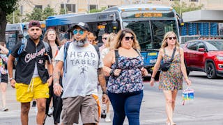 Attendees of Austin City Limits Music Festival make their way past CapMetro buses.