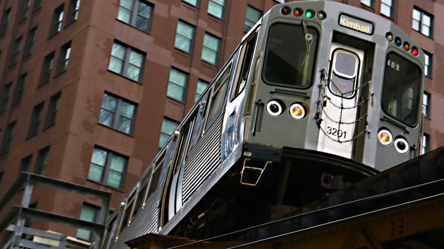 A CTA Brown Line train to Kimball travels on elevated tracks in downtown Chicago.