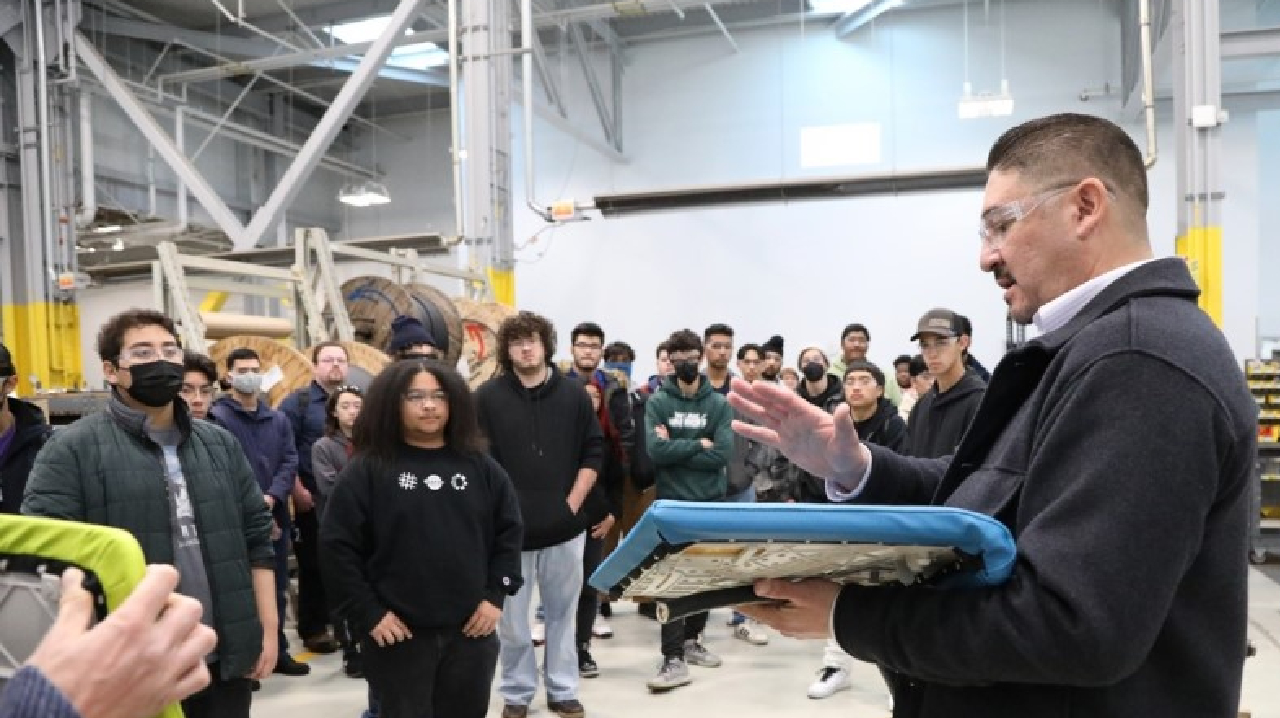 Jose Cuellar, assistant component repair maintenance shop superintendent, holds up a detached BART seat on Dec. 9, 2022, during a tour with students from Mission Valley ROP.