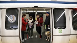 Blind and low vision riders congregate in front of an opened door in a out of service Fleet of the Future train.
