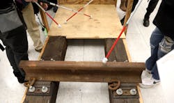 Attendees touch the mock-up of the trackway and refuge area with blind canes Attendees touch the mock-up of the trackway and refuge area with blind canes