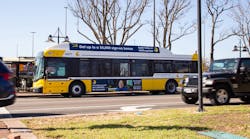 A Dallas Area Rapid Transit bus is seen driving in Downtown Dallas, Texas, with a local advertisement depicted on the side of the bus.