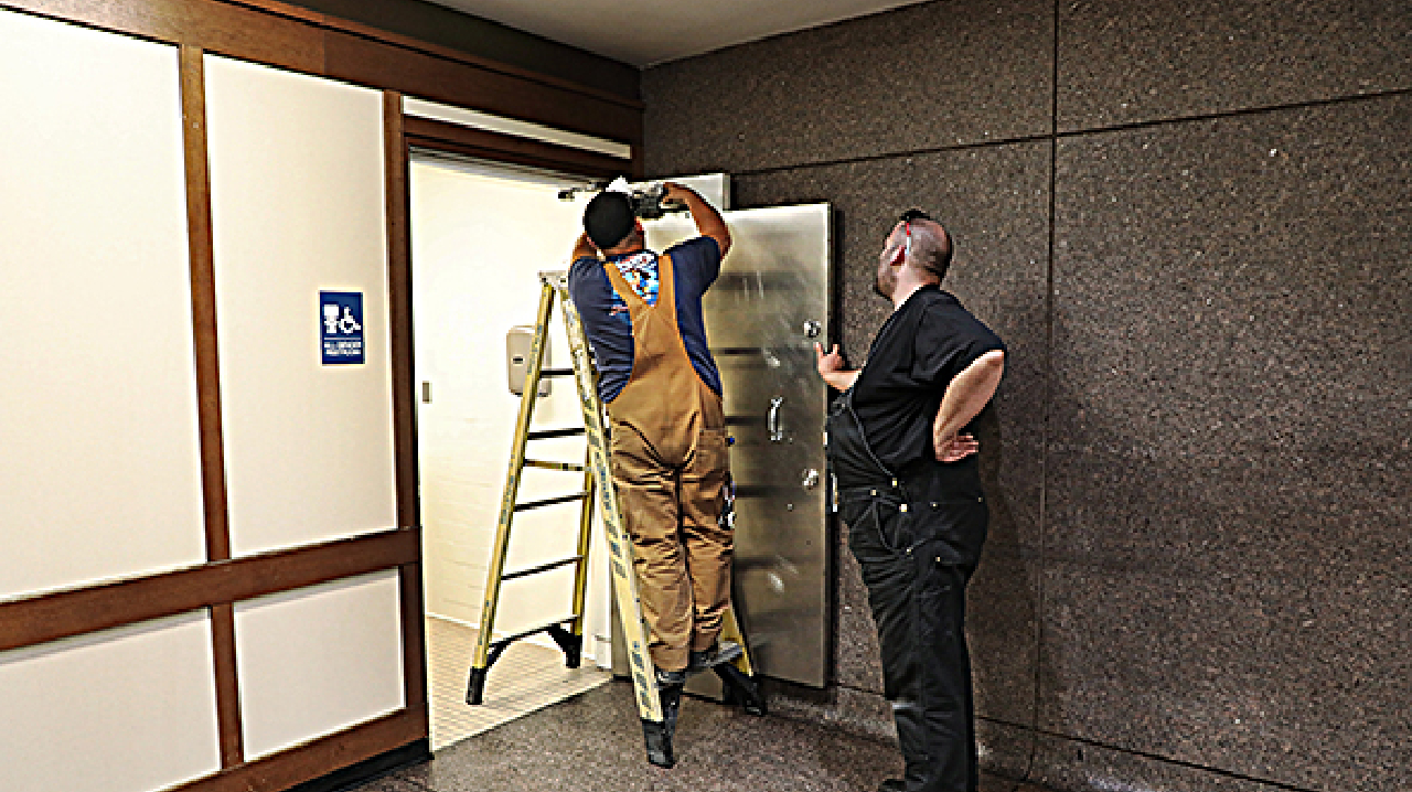 Crews put finishing touches on door at Embarcadero Station restroom.