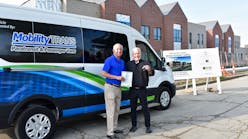 Dave Brown, general manager of MobilityTRANS, hands over the title and keys of a brand new Ford E-Transit to Fr. Tim McCabe, executive director of the Pope Francis Center.