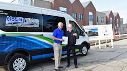 Dave Brown, general manager of MobilityTRANS, hands over the title and keys of a brand new Ford E-Transit to Fr. Tim McCabe, executive director of the Pope Francis Center.