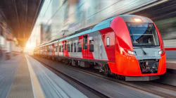 An electric passenger train drives at high speed among urban landscape.