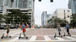 A family riding scooters crosses East Tyler Street at North Ashley Drive in downtown Tampa.