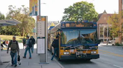 People board a route 70 bus in the U District on a sunny afternoon.