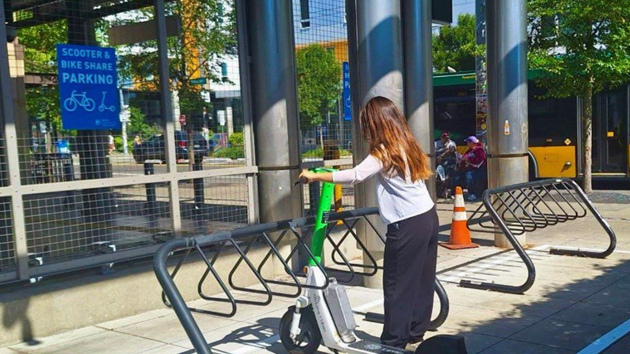 A person parks a Lime scooter in a designated parking area at the Capitol Hill Link light rail station.