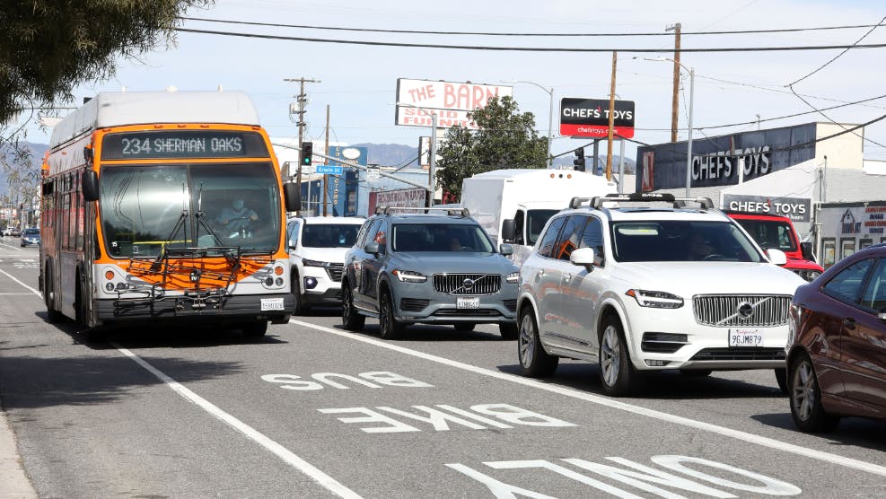 A bus in a bus lane next to cars on a freeway