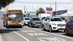 A bus in a bus lane next to cars on a freeway