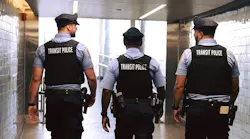 three SEPTA transit police officers walk with backs to camera at train station