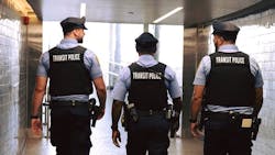 three SEPTA transit police officers walk with backs to camera at train station three SEPTA transit police officers walk with backs to camera at train station