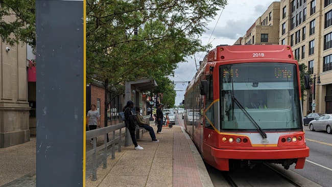 a red light rail vehicle waits at an outdoor station