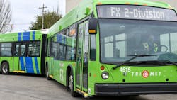 A green 60-foot TriMet bus drives down a street A green 60-foot TriMet bus drives down a street