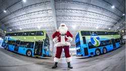 person dressed as santa stands between two double decker buses inside bus garage person dressed as santa stands between two double decker buses inside bus garage