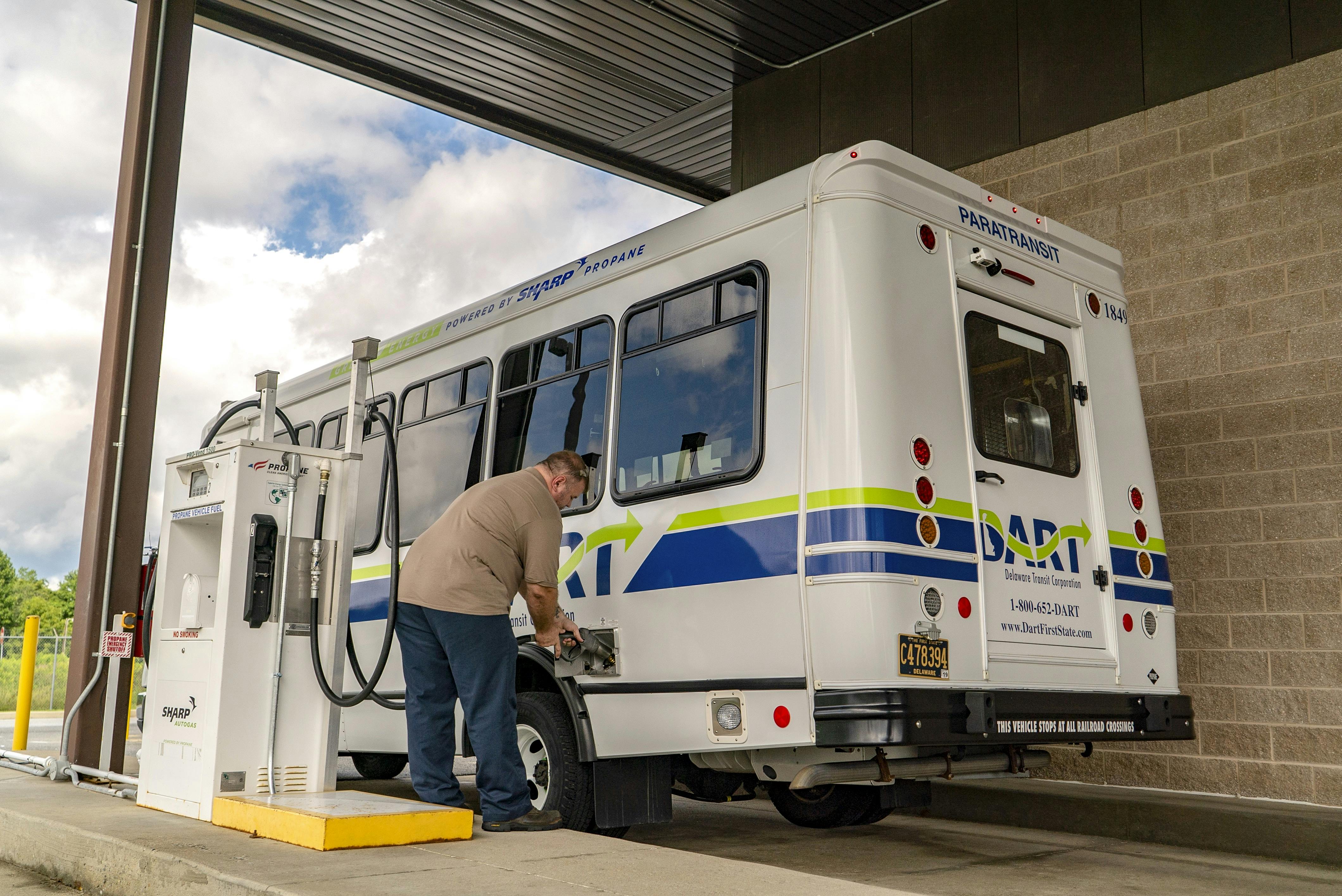 man fills up DART cutaway bus at a fuel dispenser